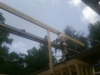 Carpenter setting a ridge beam over a new addition frame — Ice Dam Removal by Roofing Brothers in Flat Rock
