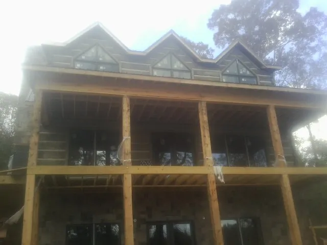 Dormers and porch framing on a large log home under construction — Roof Coating work by our crew in Flat Rock