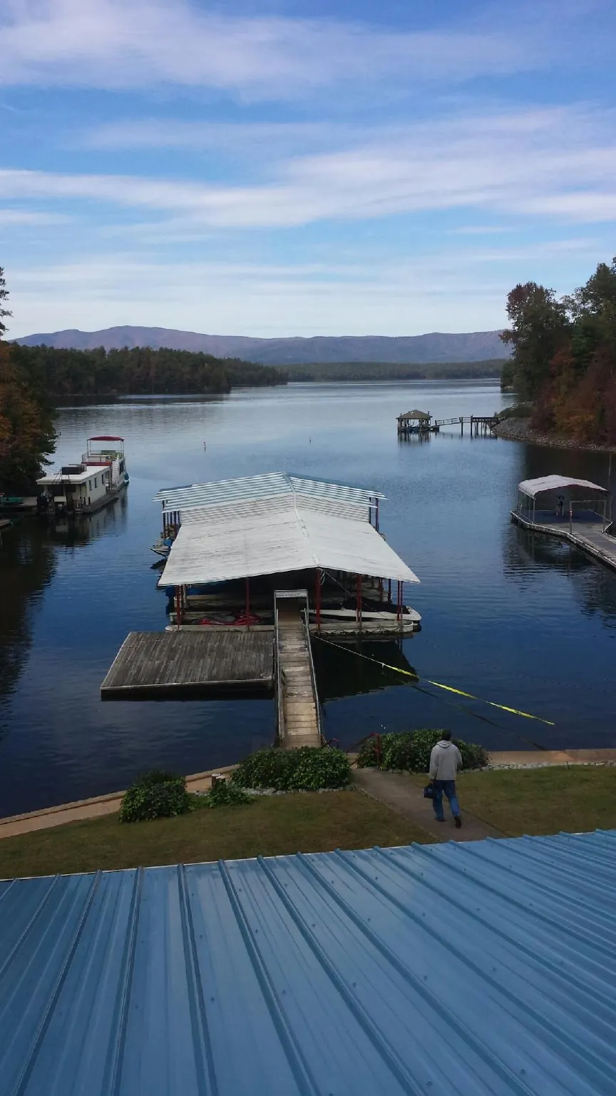 View across a lake from a newly installed blue metal roof in Flat Rock
