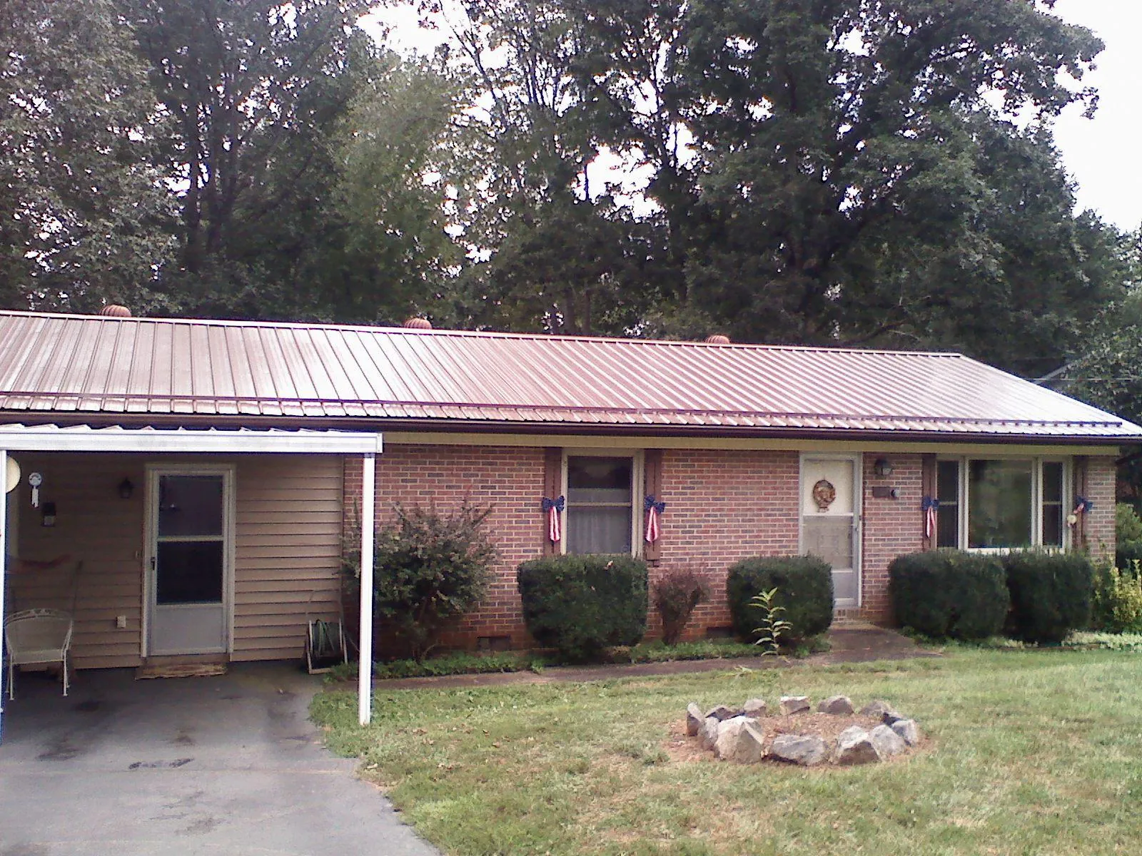Bronze metal roof and carport on a brick ranch home — Roof Repair work by our crew in Flat Rock